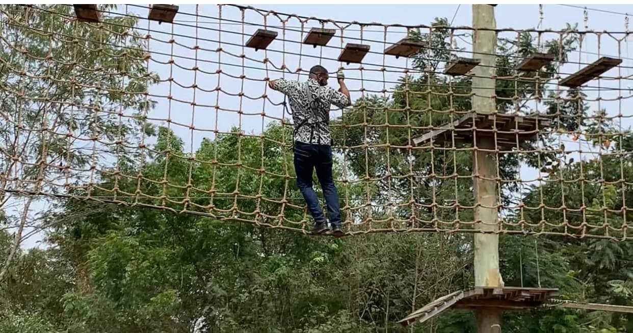 Jay Cameron crossing a high rope bridge above the treetops in Ghana