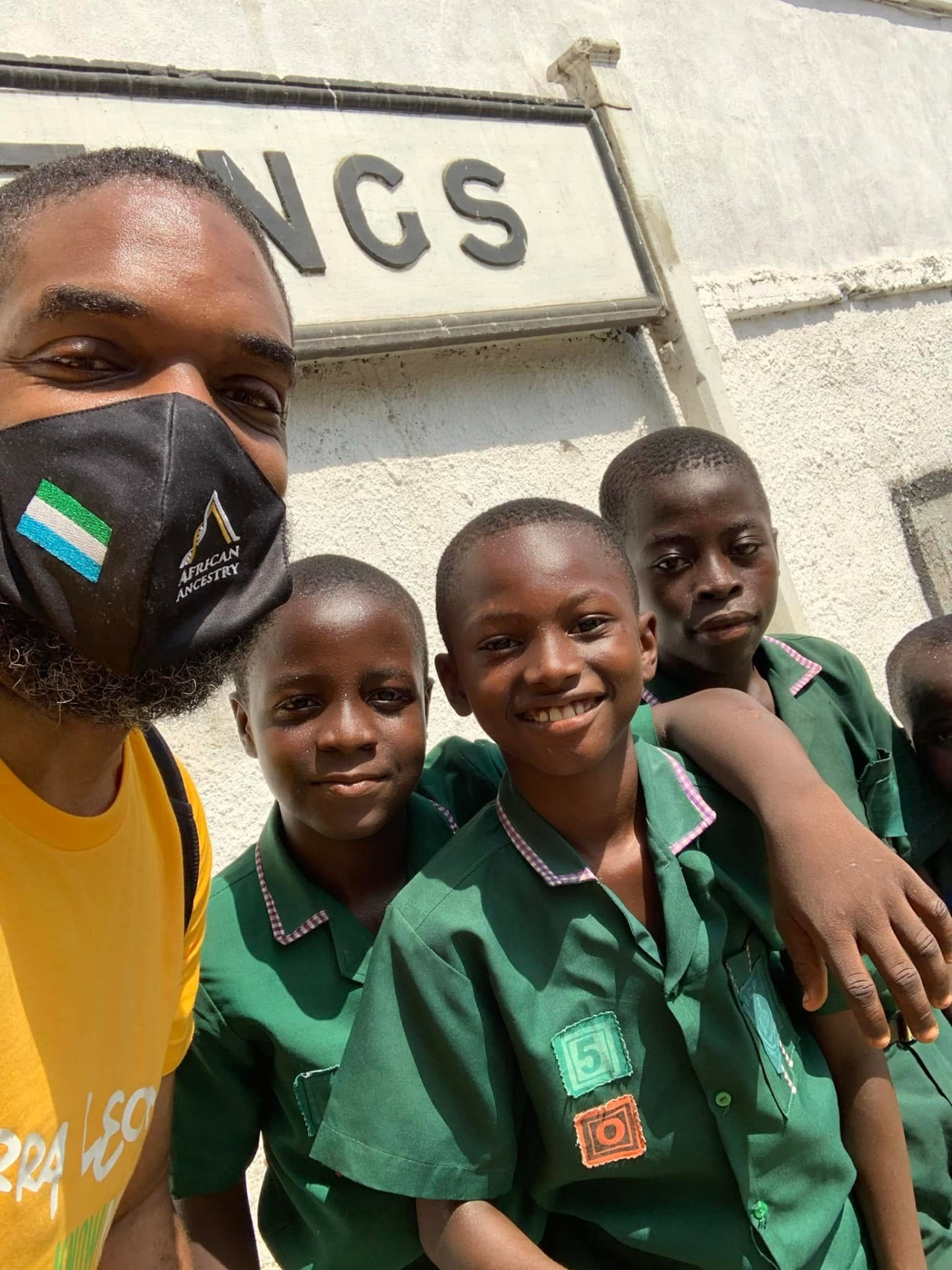 Jay Cameron outside a school building in Sierra Leone with a group of students