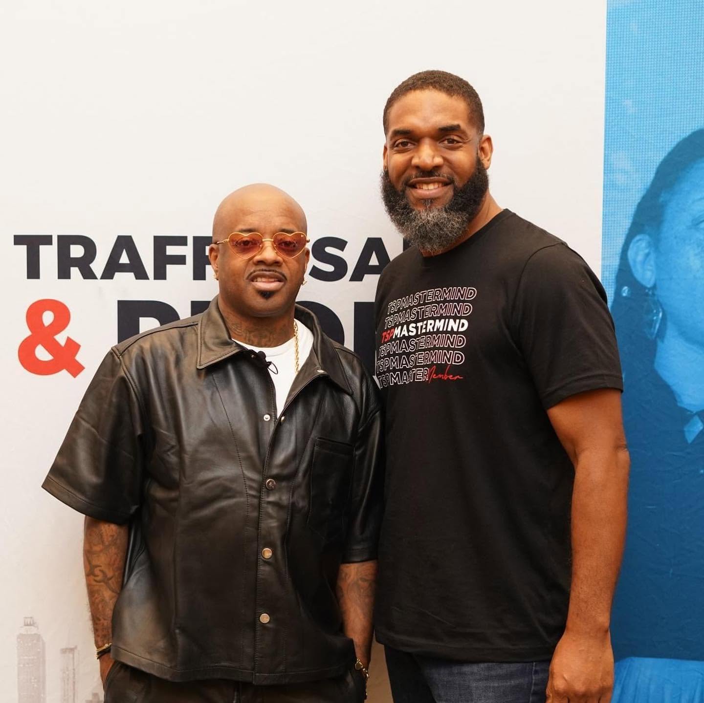 Jay Cameron at a business conference backdrop with a guest