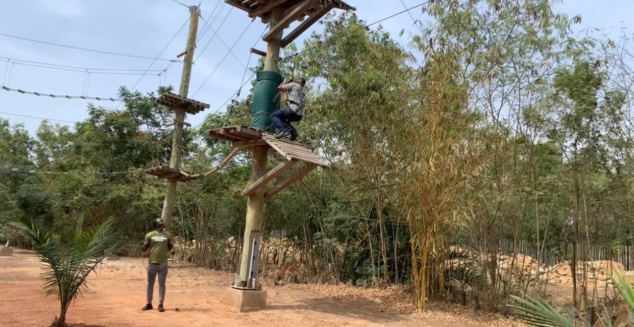 Jay Cameron climbing a high wooden platform on a rope course in Ghana