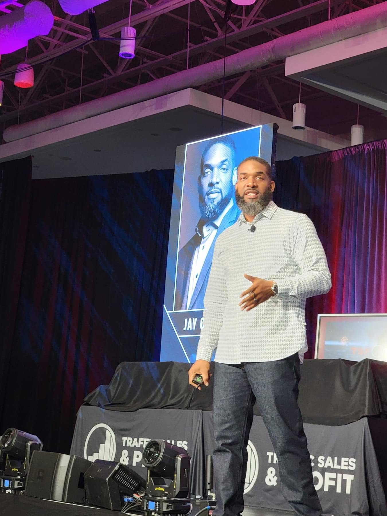 Jay Cameron speaking on stage at Traffic, Sales and Profit with his photo on the screen behind him