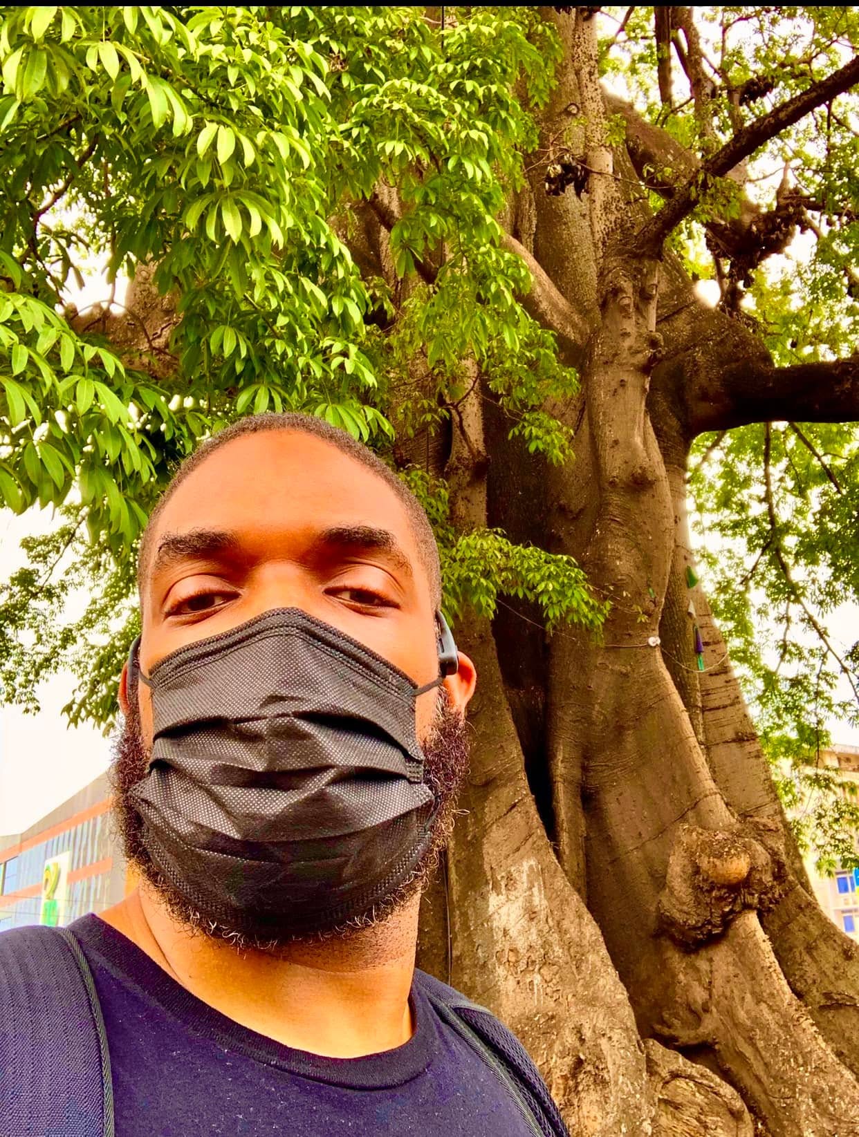 Jay Cameron standing beneath a large cotton tree in Sierra Leone