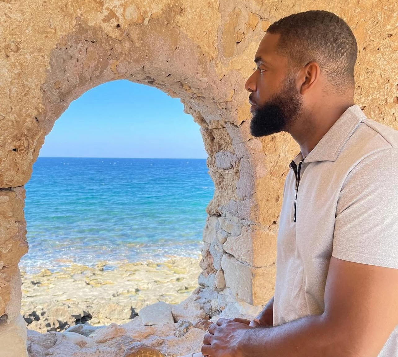 Jay Cameron looking out through a stone arch toward the sea