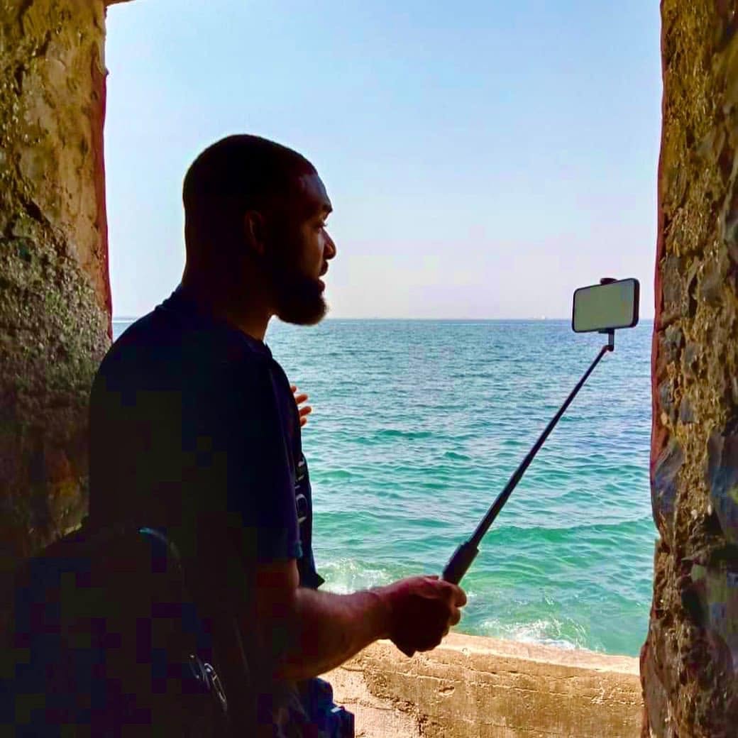 Jay Cameron filming himself in a stone doorway looking out over the sea in Senegal