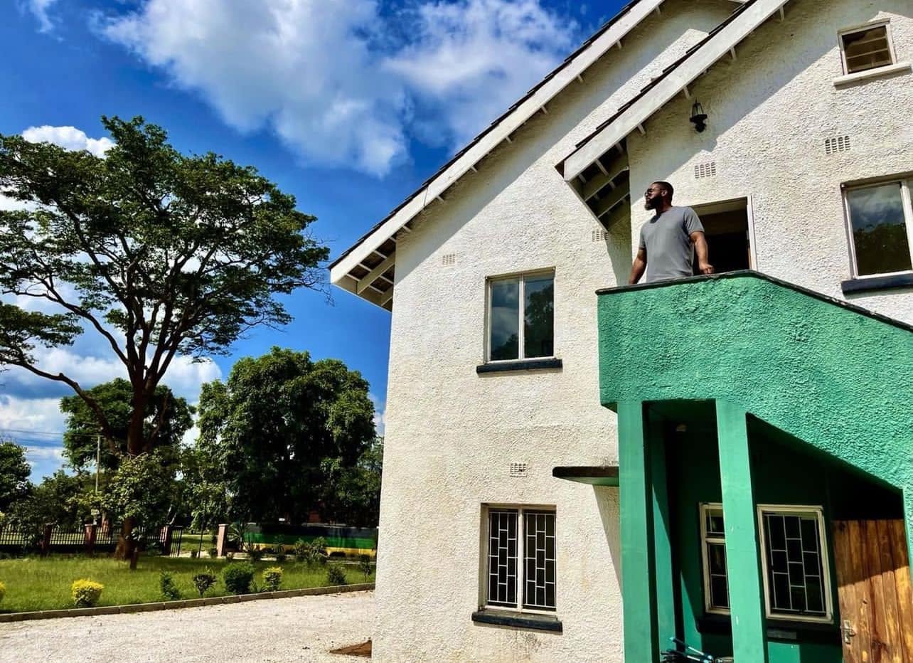 Jay Cameron standing on a green balcony of a white building in Zambia